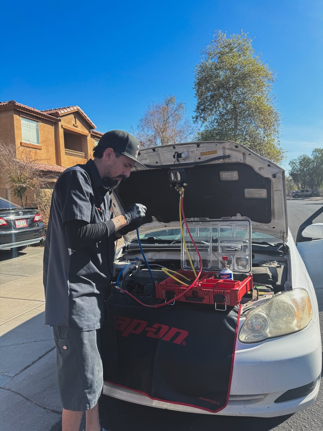 Ivan servicing the air conditioning system on a white car with manifold gauges