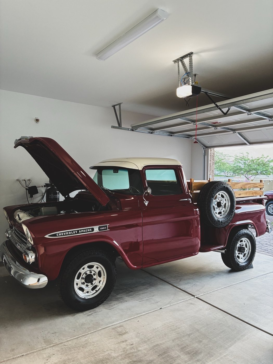 Red classic Chevrolet Apache in a garage with its hood open